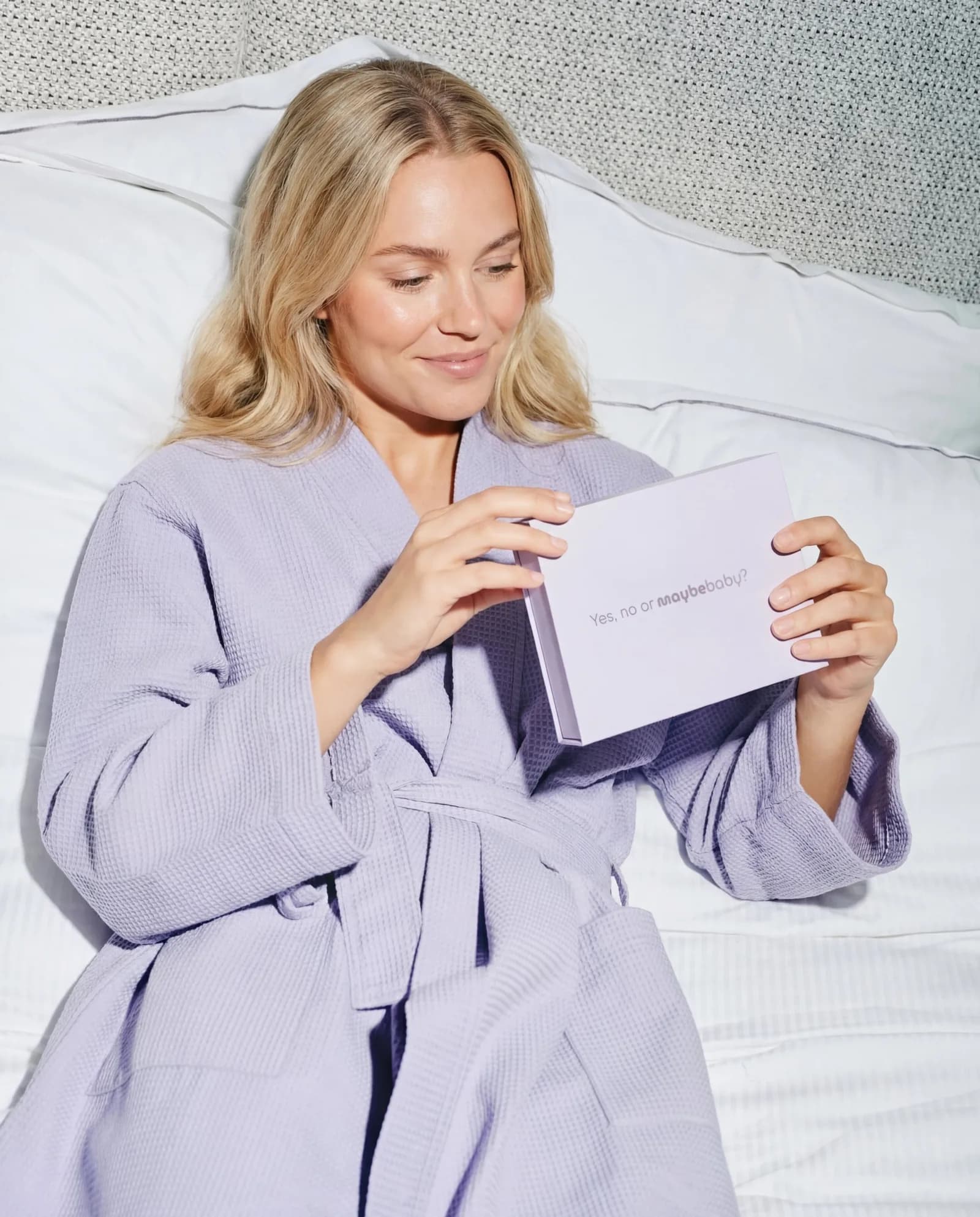 Woman in a bathrobe opening Maybe Baby's at-home fertility test in bed